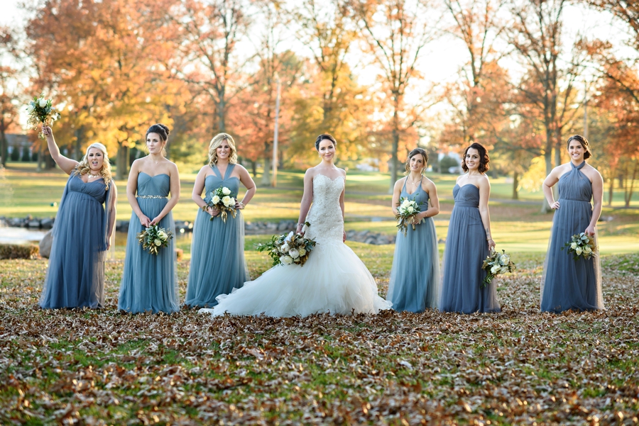 A bride and her bridesmaids standing in the fall leaves at northampton valley country club.